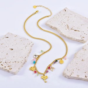 Golden elephant necklace with colorful beads and charms displayed on marble blocks