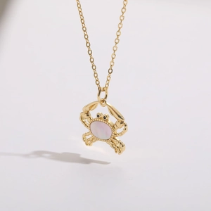 Detailed close-up of crab pendant with inlaid shell and 14K gold plating texture