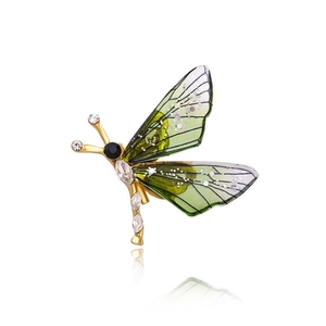 Detailed macro view of a golden dragonfly brooch with sparkling green gradient wings