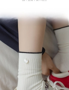Detail of knit ribbed crew socks with contrast trim and shell button accent