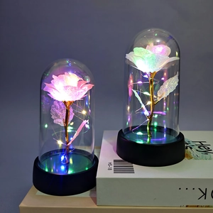 Detail of colorful galaxy rose in glass dome with warm LED copper lights and black base