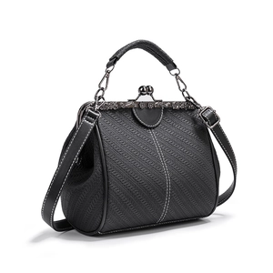 Detail view of woven texture and vintage metal clasp on a black PU leather handbag