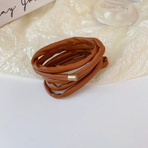 Detailed view of a brown faux leather hair bun maker with elegant gold metal buckles