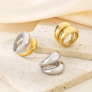Macro view of polished 18K gold and silver chunky rings on beige marble tray