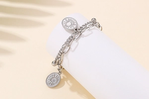 Detail of double-layer stainless steel bracelet with sun pendant on white cylinder