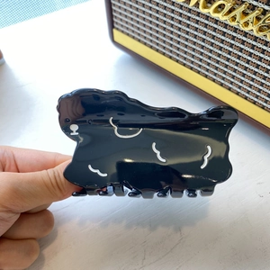 Detail shot of a black cartoon puppy claw clip made of shiny acetate with white outlines