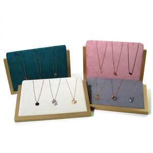Navy, pink, white, and gray velvet necklace displays with brushed gold metal frames