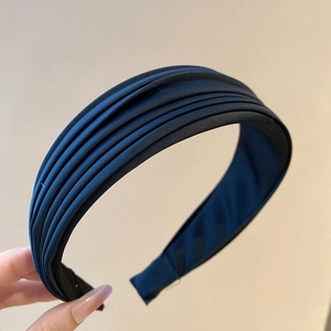 Détail des plis en satin bleu marine superposés et de la doublure du serre-tête