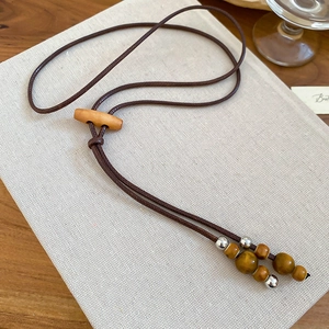 Detail of vintage bohemian wax cord necklace with wood beads and silver metal accents