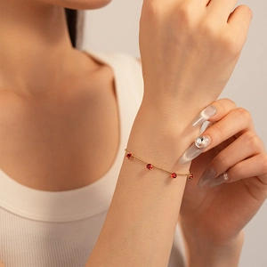 Elegant gold beaded bracelet featuring four round red gemstones on a feminine wrist