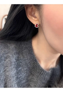 Close-up of red hulu stud earring with sparkling cubic zirconia on female model