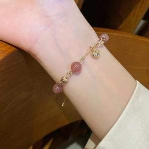Detail of pink strawberry quartz heart bracelet on woman's wrist in elegant lighting