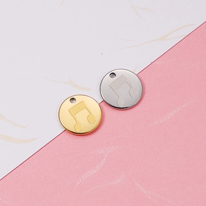 Detail of round gold and silver stainless steel pendants with musical note engravings