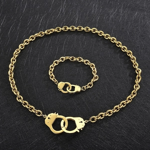 Close-up of gold stainless steel necklace and bracelet set with handcuff design