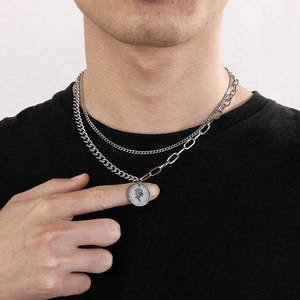 Detail of layered silver coin necklace with Elizabeth II engraving on a black shirt