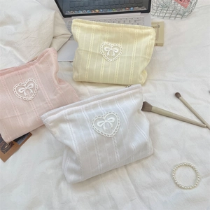 Detail of candy-colored makeup bags with lace bow heart patches and ribbed knit texture