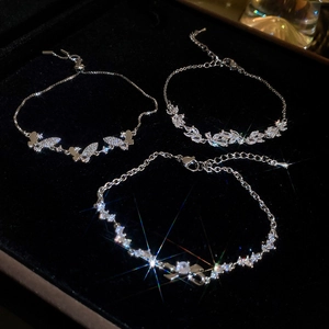 Detailed close-up of three sparkling zircon flower and butterfly bracelets on black velvet