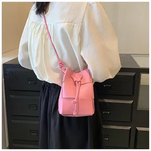 Detail of pink woven leather bucket bag with drawstring closure and slim shoulder strap