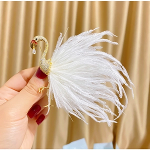 Close-up of golden flamingo brooch with crystals and soft white feathers detail