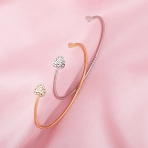 Detail of heart-shaped open bracelets with white crystals on pink silk background