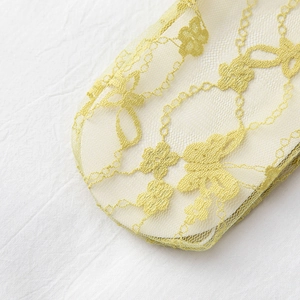 Detail of light yellow lace mesh socks with floral embroidery and breathable texture