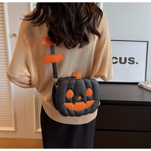 Detail of a black pumpkin-shaped crossbody bag with orange bat charms on the strap