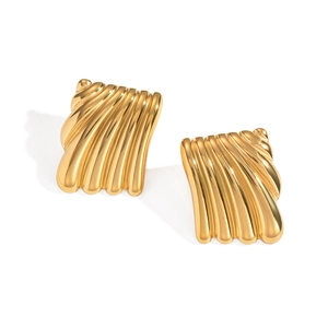 Détail de boucles d'oreilles carrées dorées à texture ondulée sur fond blanc neutre