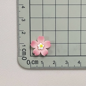 Close-up of 2cm pink resin cherry blossom accessories with dimensions on a cutting mat