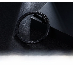 Detailed close-up of men's black braided leather bracelet with magnetic steel clasp