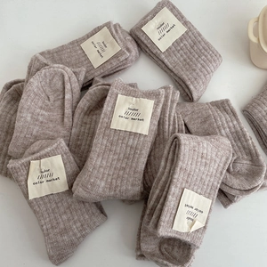 Close-up of stacked light brown wool blend socks with stitched fabric brand labels