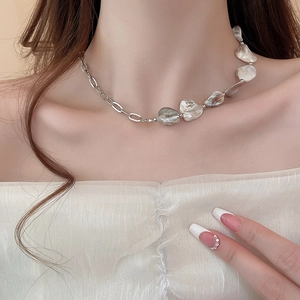 Dettaglio della collana a catena argentata con perle barocche e conchiglie su una modella