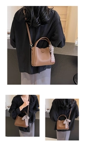 Detailed view of brown litchi grain leather bucket bag with black and white plaid scarf