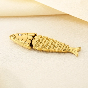 Détail d'un pendentif poisson doré avec textures d'écailles et un œil en strass brillant