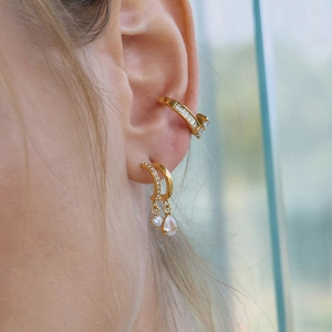 Close-up of gold drop earrings and ear cuff with clear cubic zirconia on person