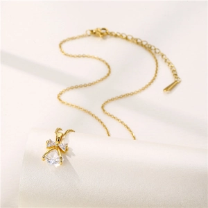Elegant gold bow necklace with clear zircon crystals on soft beige silk background