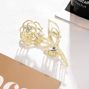 Detailed close-up of golden rose hair claw with sparkling rhinestone floral design