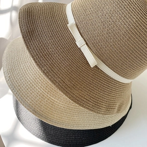 Three minimalist straw sun hats with bows in dark coffee, cream, and black colors