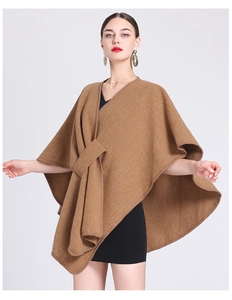 Fashionable camel knit poncho cape with knot detail styled over a black midi dress