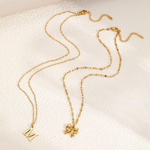 Golden double-layer necklace with bow pendant and initial M on frosted background