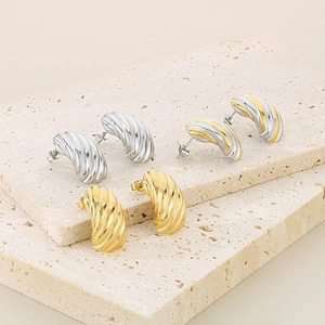 Détail des boucles d'oreilles C à rayures en finitions dorée, argentée et bicolore