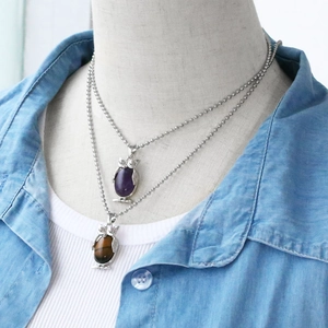 Detail of double owl pendant necklace with purple and brown stones on silver bead chain