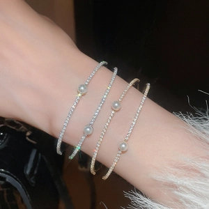 Detail of elegant double-layer bracelets with shiny zircons and pearls on wrist