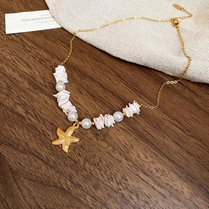 Close-up of ocean-style necklace with gold starfish pendant, pearls and shells