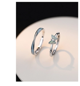 Macro shot of silver luminous butterfly rings with blue enamel inlay for couples on beige disk
