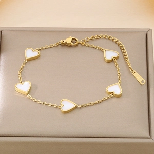 Close-up of gold stainless steel bracelet with five white heart shell charms in a gift box
