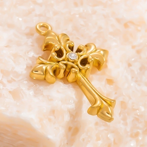 Macro di un ciondolo a croce in acciaio placcato oro 18k con delicato rilievo floreale