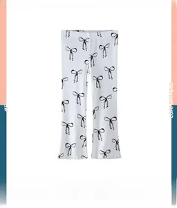 Détail du legging en tricot blanc pour filles avec imprimés nœuds noirs et bords volantés