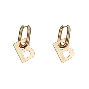 Macro detail of high-polish gold hoop earrings featuring hanging letter B charms