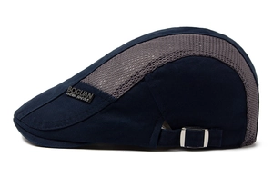 Detail of dark blue mesh newsboy cap with metal brand plate and adjustable side buckle