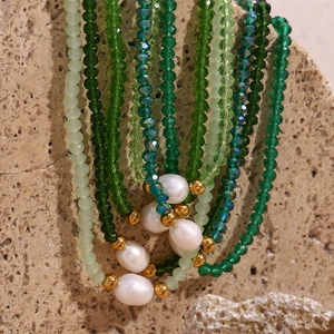 Detail of green beaded necklace with freshwater pearls and gold beads on stone